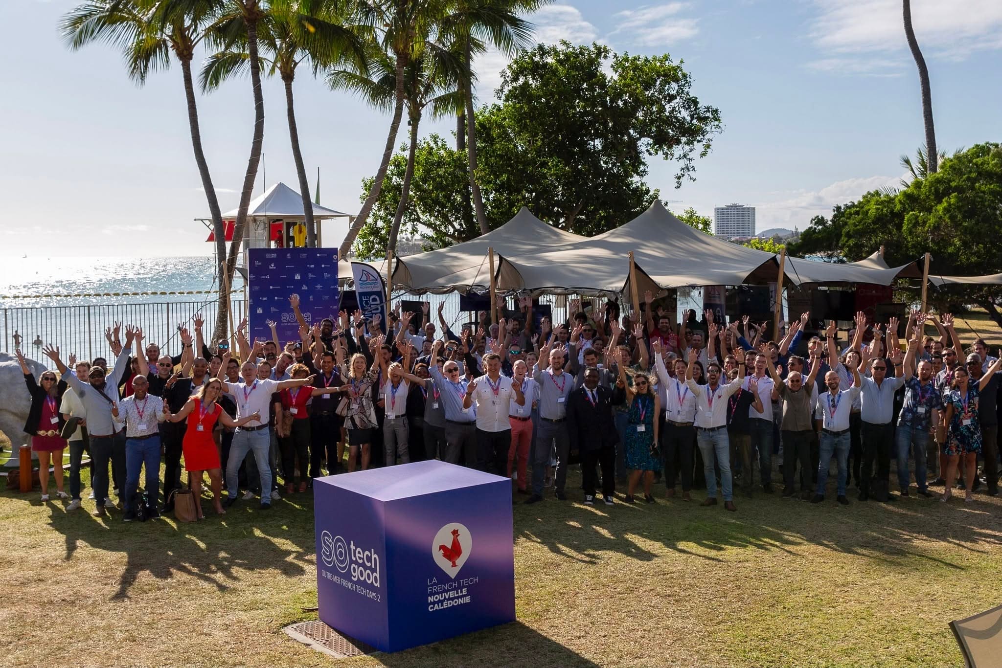 Les participants d’un événement de La French Tech Nouvelle-Calédonie, bras levés, en bord de mer à Nouméa