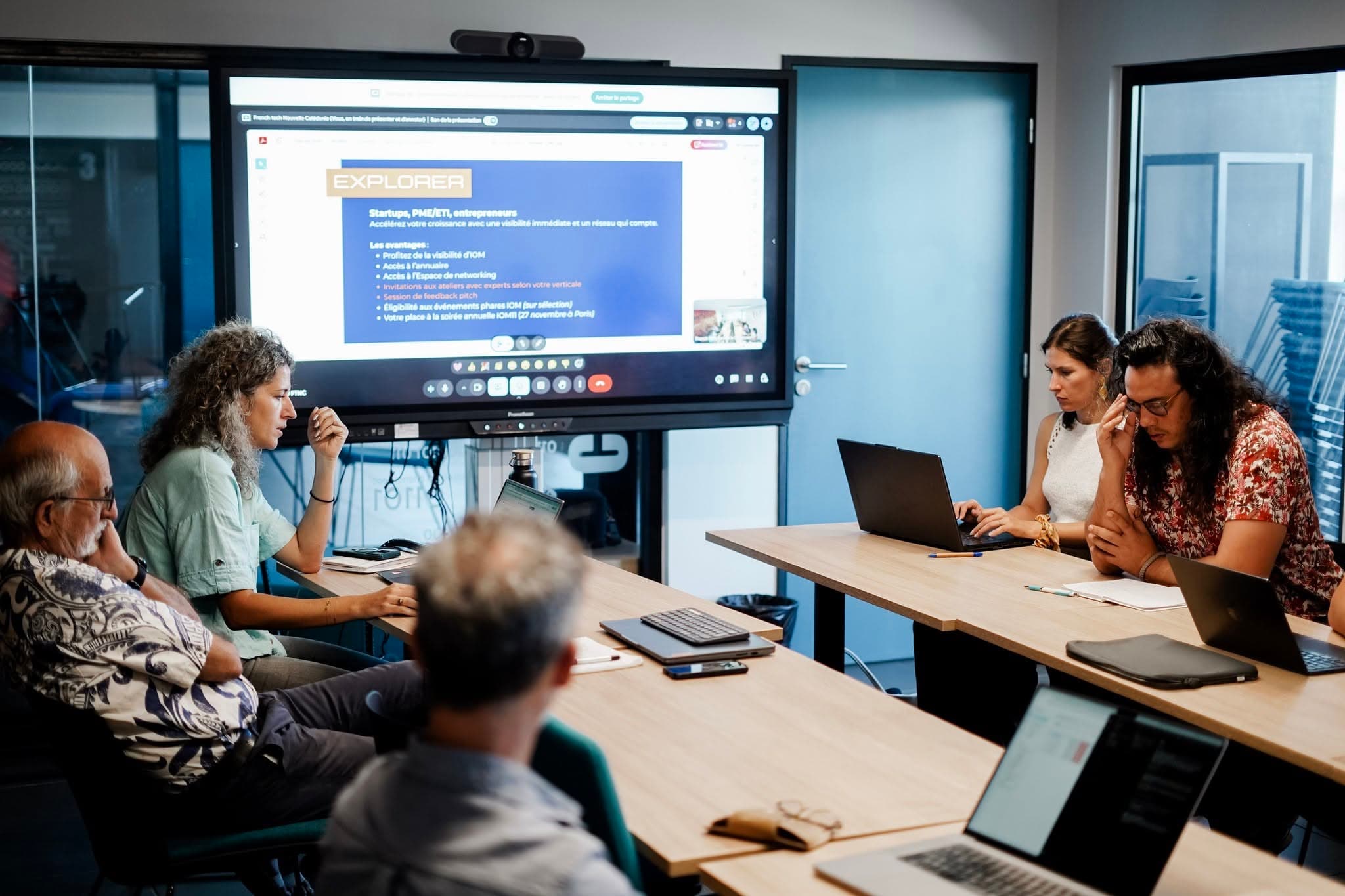 Un atelier de travail autour d’une table, devant un écran de présentation